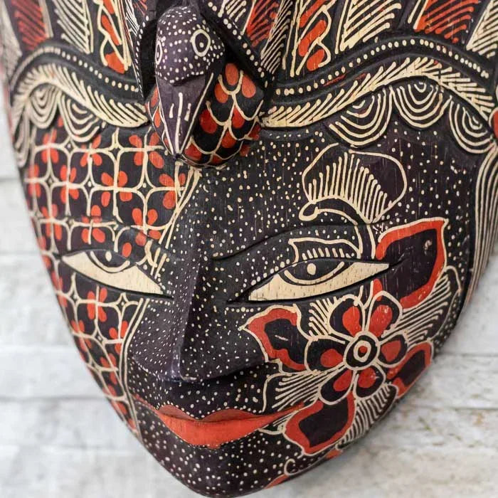 Máscara balinesa entalhada em madeira com pintura Batik em tons contrastantes, trazendo simbolismo e expressão artística
