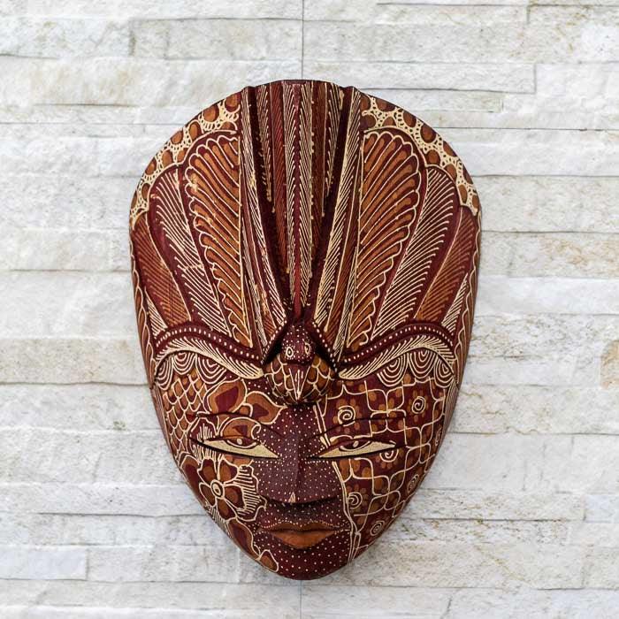 Máscara decorativa com traços delicados em madeira e acabamento Batik, perfeita para compor ambientes com identidade cultural