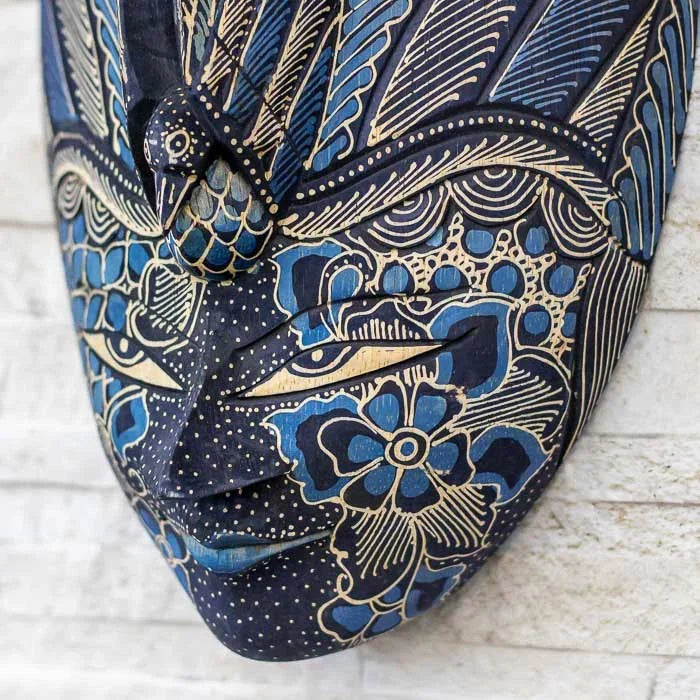 Máscara em madeira com traços elegantes e pintura Batik colorida, representando a fusão entre arte e espiritualidade balinesa
