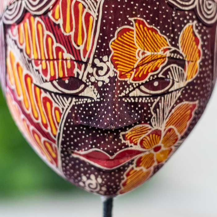 Escultura javanesa pintada à mão com técnica batik e entalhes refinados.