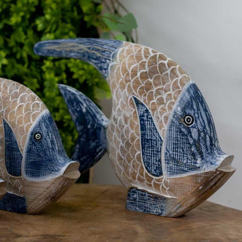 Esculturas artesanais de peixes em madeira com acabamento em pátina.