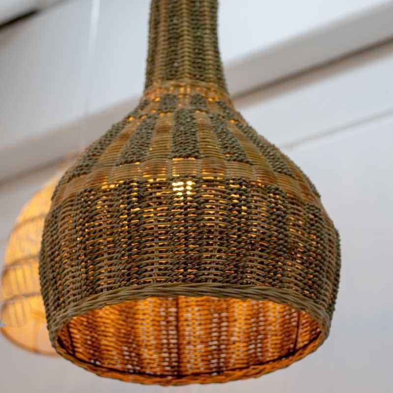 Luminária de fibra sustentável suspensa, projetando luz através do trançado aberto para gerar efeitos de sombra em paredes claras.