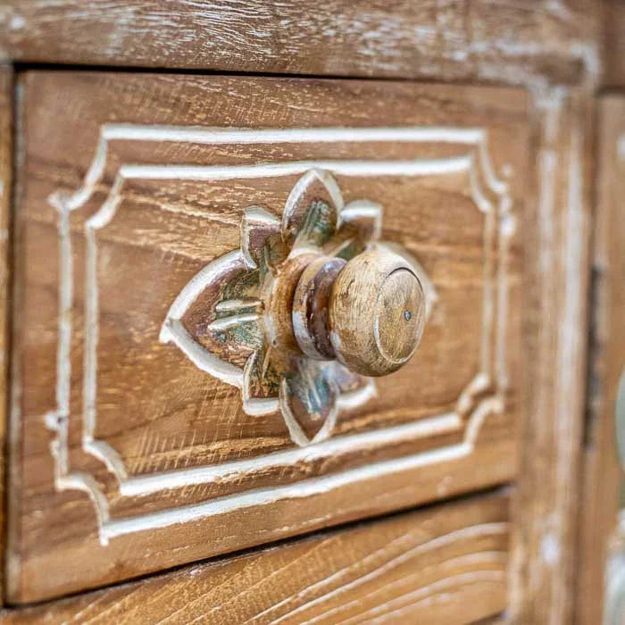 Detalhe de aparador curvo com três gavetas centrais, destacando os entalhes florais manuais na madeira.