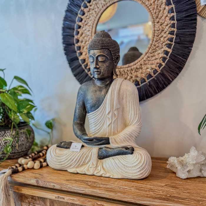Escultura artesanal de Buda meditando com manto kasaya e textura leve produzida em Bali para decoração zen.