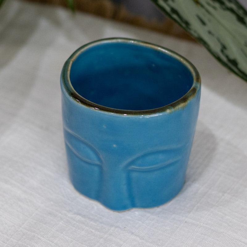 Utensílio artesanal em cerâmica azul com design de face balinesa.