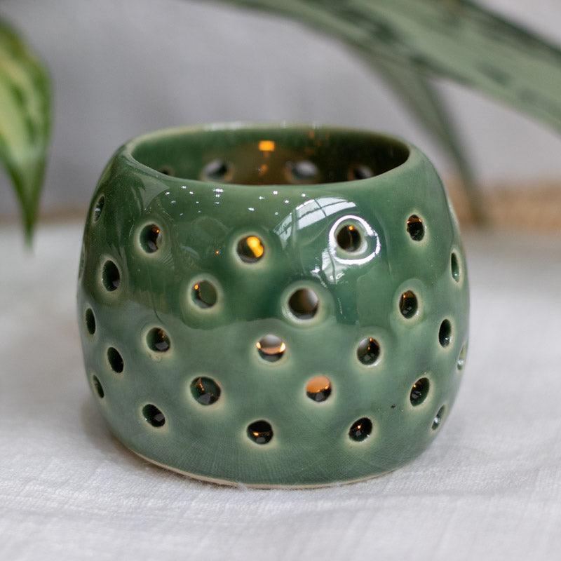 Peça decorativa verde com furos vazados para iluminação suave