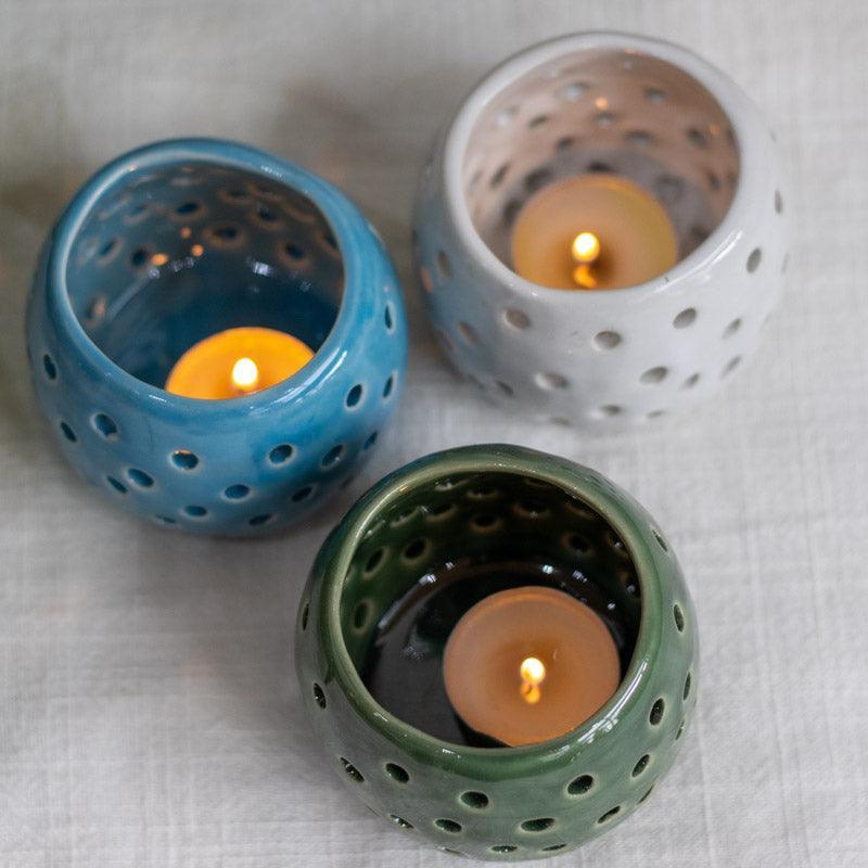Vela acesa iluminando interior de porta-velas em cerâmica balinesa