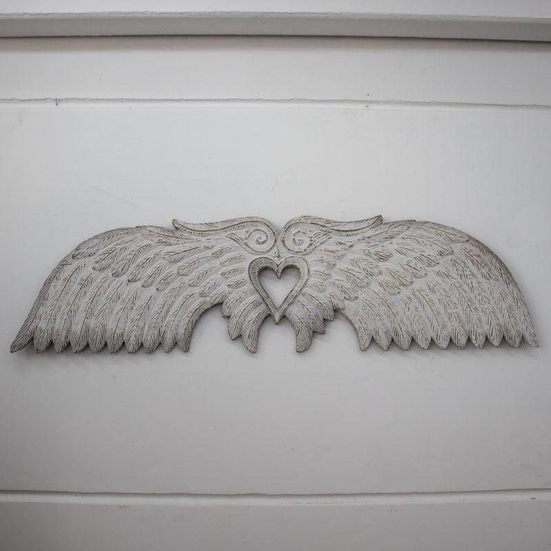 Detalhe do coração vazado unindo as duas asas esculpidas, peça que traz harmonia e paz para o design de interiores.
