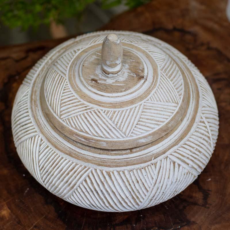 Arte balinesa representada em potes de madeira com acabamento em pátina, peças decorativas com relevos geométricos e tampa artesanal de design tribal.