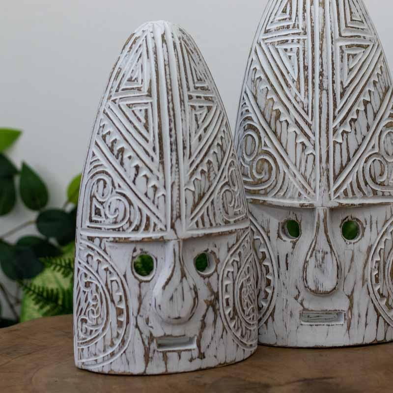 Máscara artesanal timorense feita à mão em madeira natural, com acabamento em pátina branca e entalhes culturais que expressam tradição e simbolismo étnico.