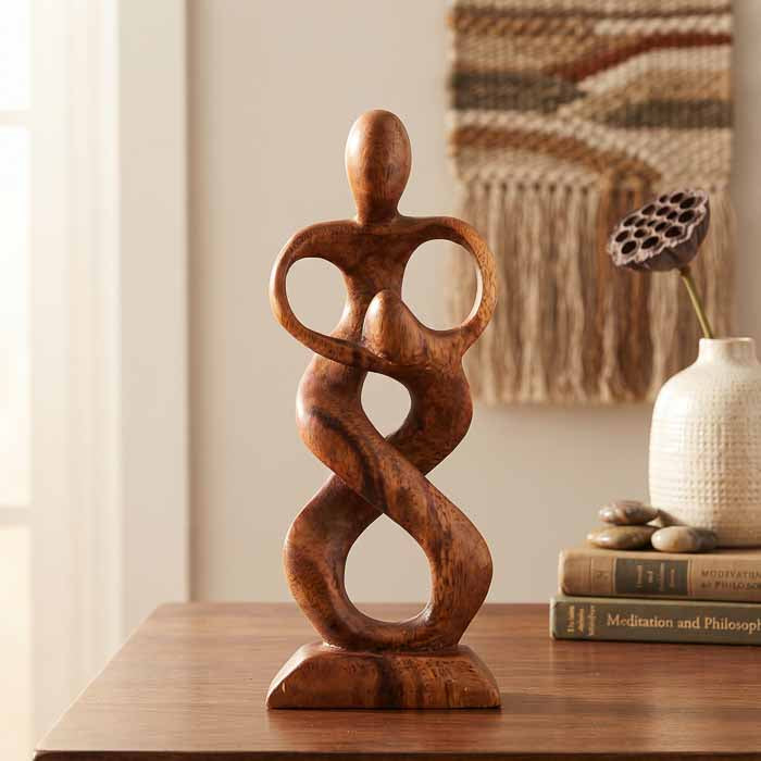 Escultura artesanal abstrata do Amor Paterno em madeira de Teca maciça representando pai e filho sobre mesa.