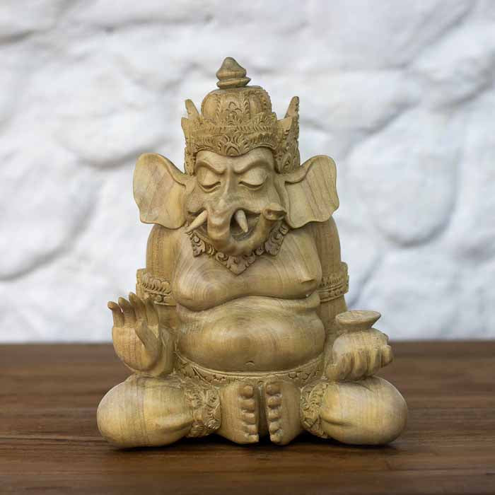 Escultura artesanal da divindade Ganesh em madeira Crocodile marfim sentada em posição meditativa sobre mesa.