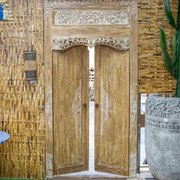 Porta artesanal entalhada em madeira natural de Bali com pátina branca, peça única que une tradição cultural e elegância artesanal.