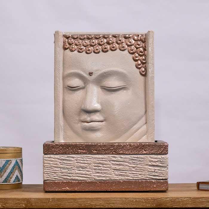 Fonte de água artesanal com o rosto sereno de Buda em terracota.