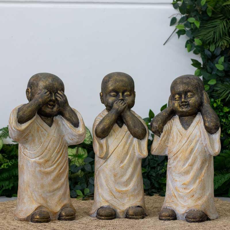 Trio de estátuas de monges budistas da sabedoria esculpidas em fibrocimento cinza de Bali.