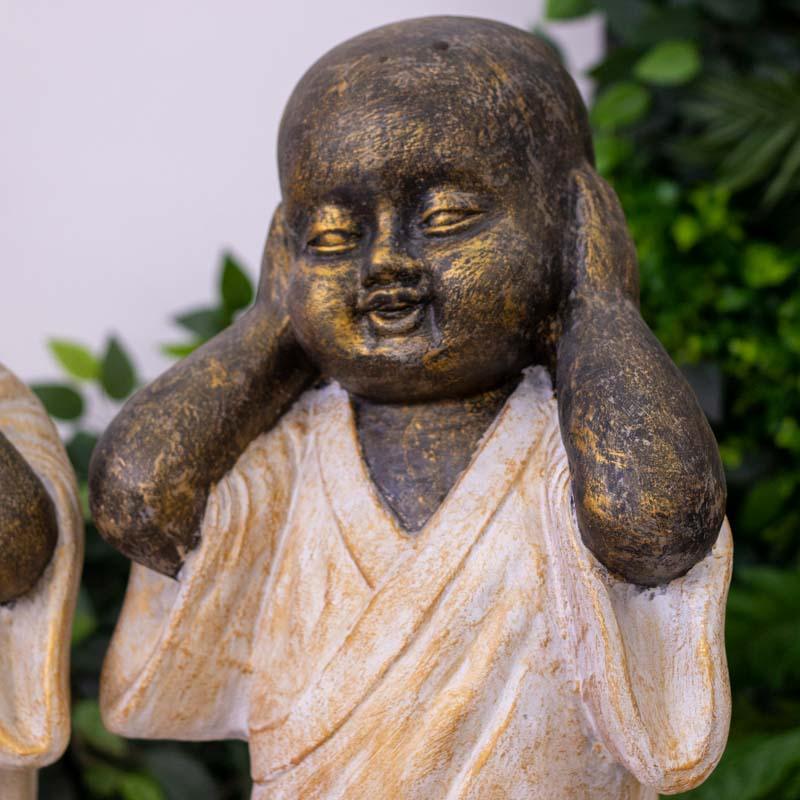 Monge sábio de Bali cobrindo os ouvidos em postura meditativa de fibrocimento.