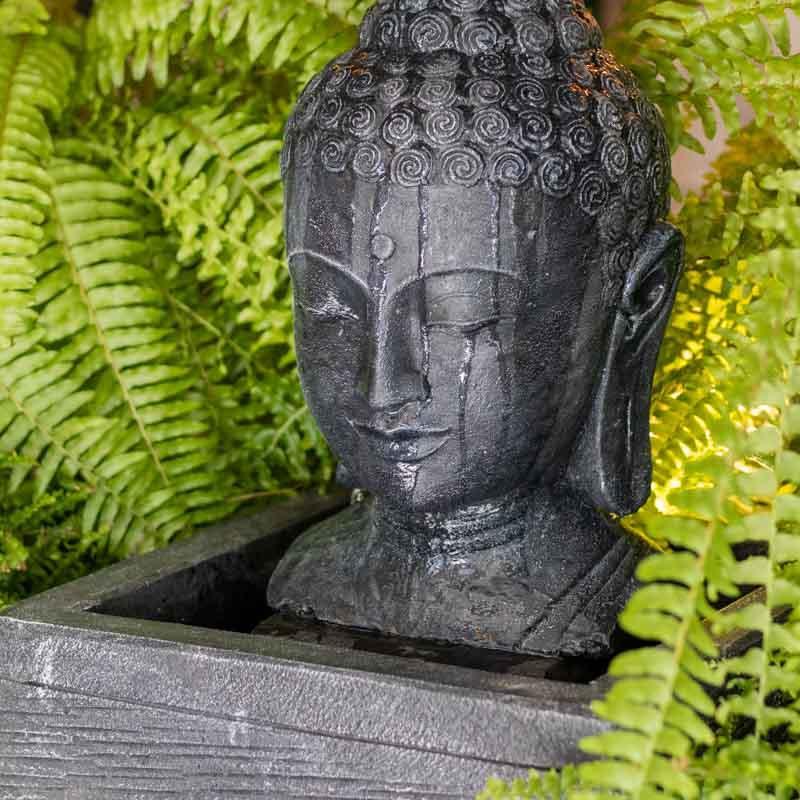 Detalhe da face serena de Buda em fonte artesanal de Bali com acabamento preto acetinado.
