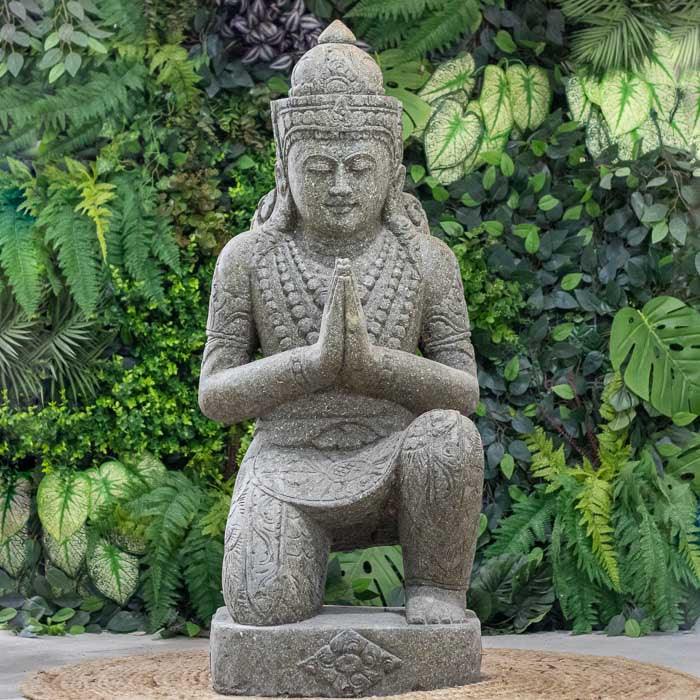 Escultura Buda Namastê entalhada em pedra natural, feita à mão em Bali com acabamento artesanal.