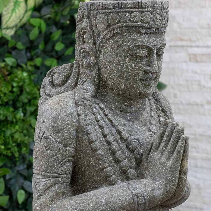 Obra balinesa feita em pedra com traços serenos e postura simbólica do Buda.