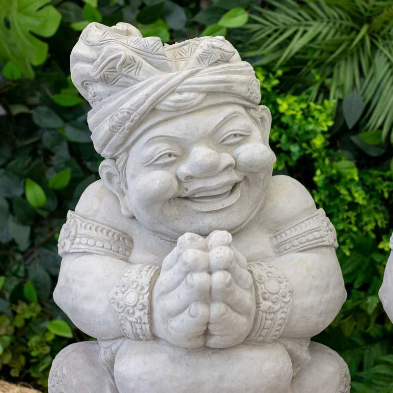 Par de esculturas artesanais Bolo Bolo feitas em pedra Limestone de Bali, com figuras sorridentes em gesto de saudação.
