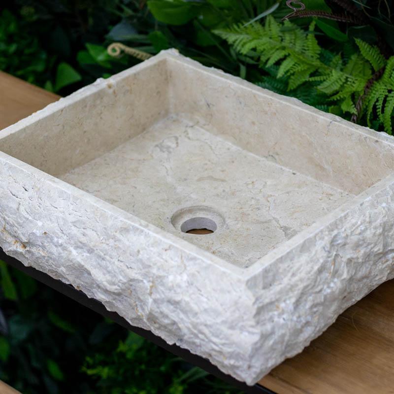 Cuba de pia quadrada artesanal feita em mármore bege natural de Bali, com interior polido e exterior em pedra bruta.