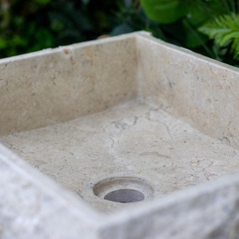 Detalhe da textura rústica externa em cuba de mármore de sobrepor, destacando a beleza da rocha natural esculpida à mão.