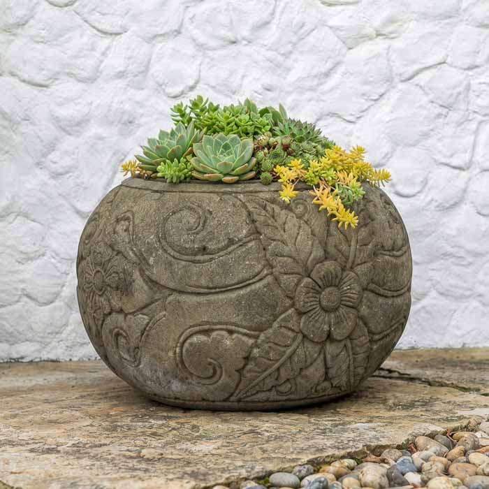 Vaso esférico em pedra vulcânica cinza com entalhes florais em alto-relevo esculpidos à mão.