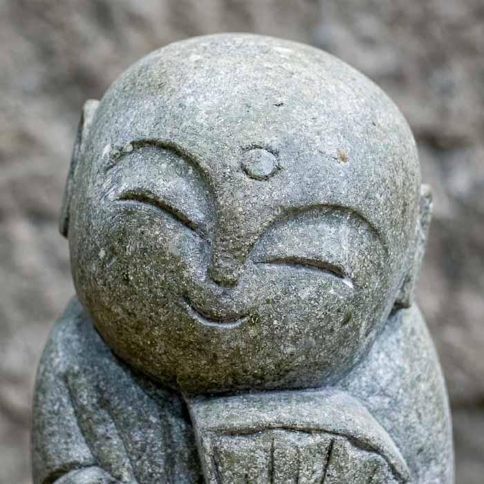 Estátua de 60cm de altura em Green Stone integrada a ambiente de jardim com tons terrosos.