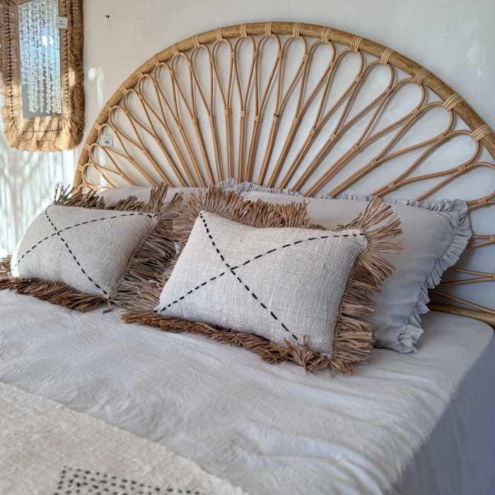 Almofada artesanal boho em fibra natural com franjas de palha.