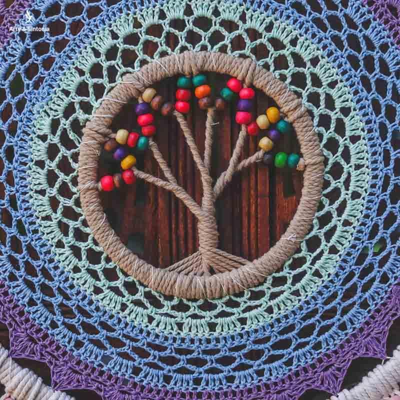 Filtro dos sonhos em macramê com árvore central e contas coloridas.