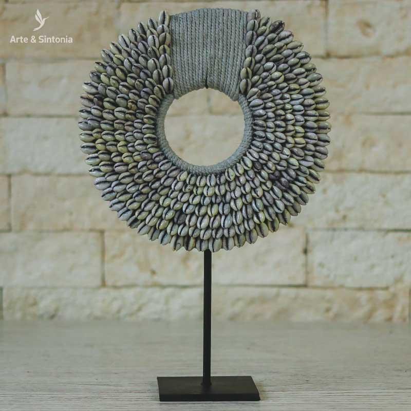 Colar artesanal de Bali em pedestal com búzios decorativos.