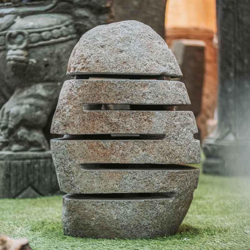 Decoração de jardim zen com luminária de pedra natural integrada à vegetação.