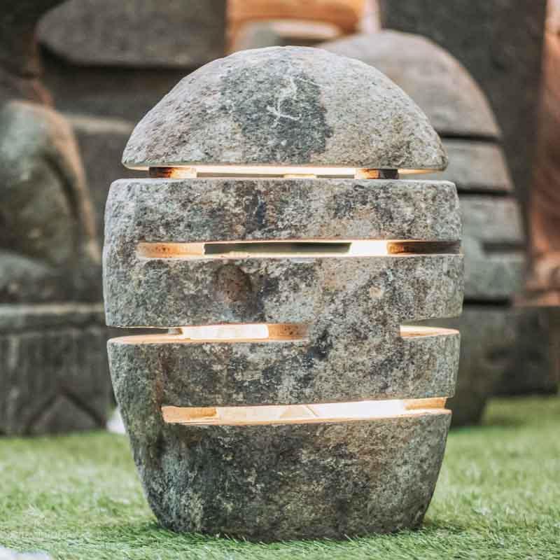 Luminária de chão esculpida em pedra de rio natural com fendas para passagem de luz.