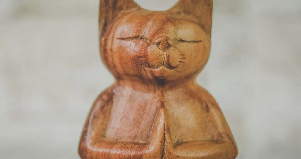Escultura feita manualmente em madeira de gato em pose namastê.
