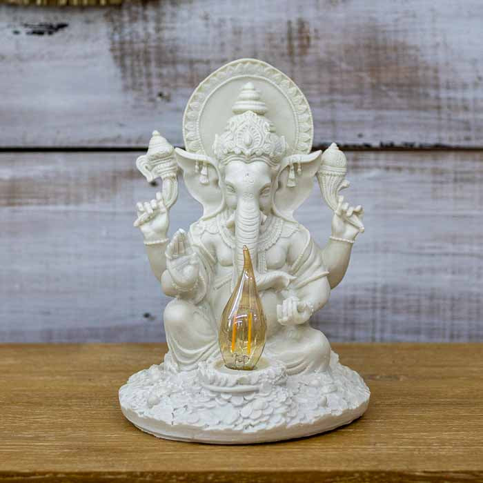 Divindade hindu Ganesha esculpida em material liso com brilho natural de pedra posicionado em um altar zen.