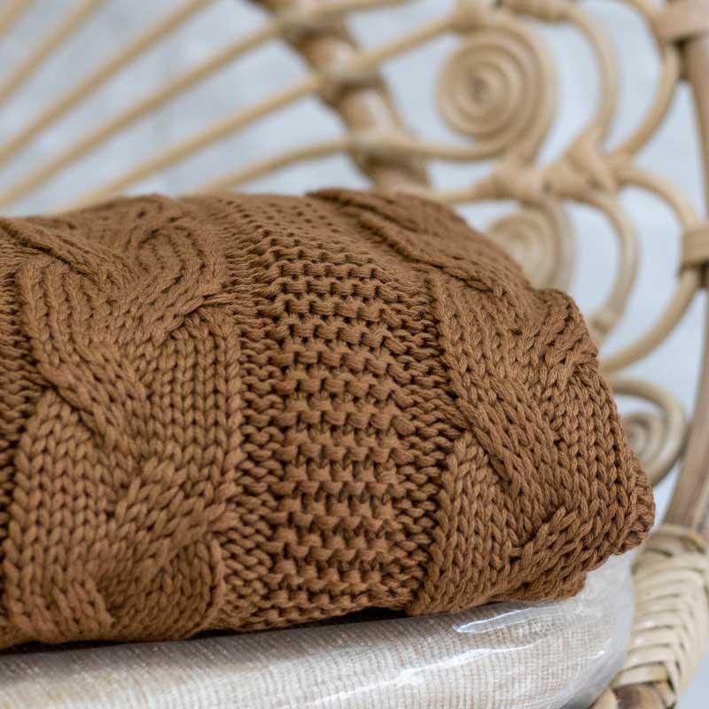 Detalhe da trama macia e volumosa de manta de tricô marrom para decoração de salas e quartos. 