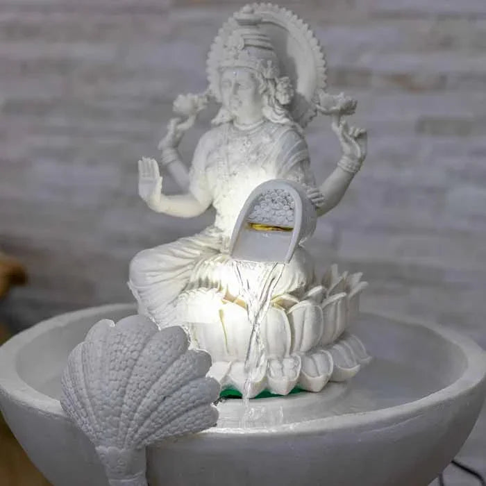 Detalhe da água corrente na fonte de marmorite em ambiente zen decorado com plantas e elementos naturais.
