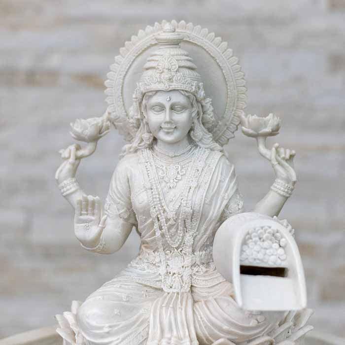 Fonte decorativa de grande porte com Deusa hindu da fortuna posicionada em hall de entrada sofisticado.