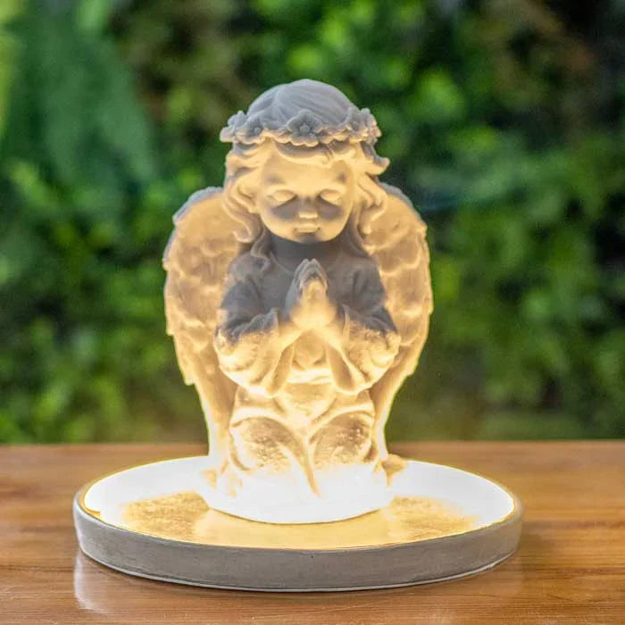 Escultura de anjo branco em oração com base iluminada em luz suave