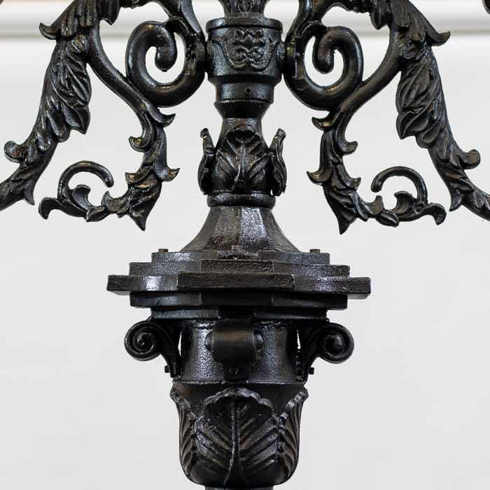 Poste de iluminação externa com pedestal trabalhado em relevos artísticos de ferro fundido.