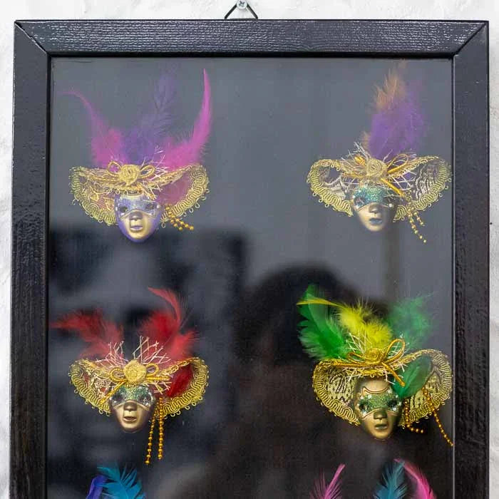 Painel de galeria com miniaturas artesanais de máscaras europeias, ideal para decoração sofisticada de interiores.