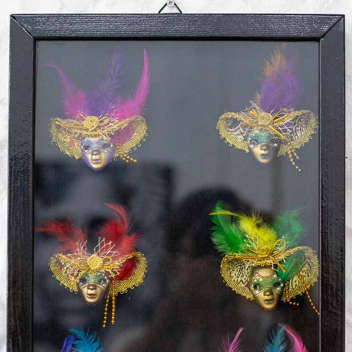 Painel de galeria com miniaturas artesanais de máscaras europeias, ideal para decoração sofisticada de interiores.