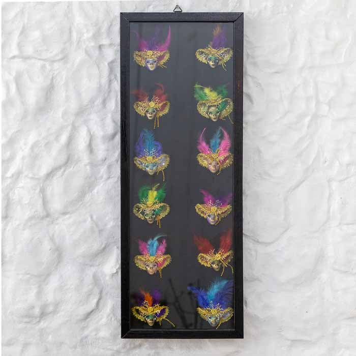 Painel vertical emoldurado com 12 miniaturas de máscaras do Carnaval de Veneza decoradas com penas coloridas.