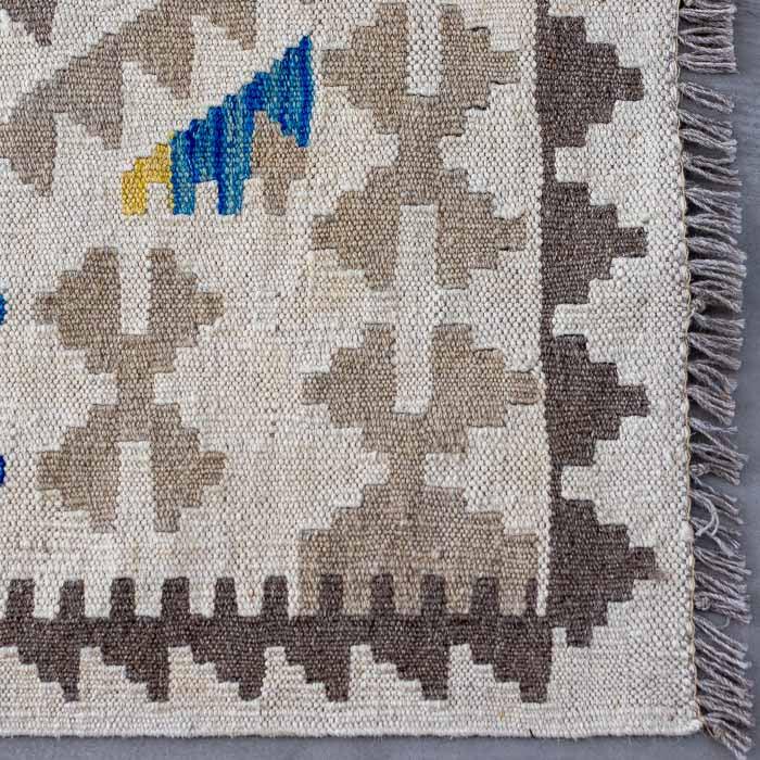 Peça de arte têxtil exclusiva tecida à mão, apresentando franjas curtas e design étnico sofisticado para interiores de alto padrão.