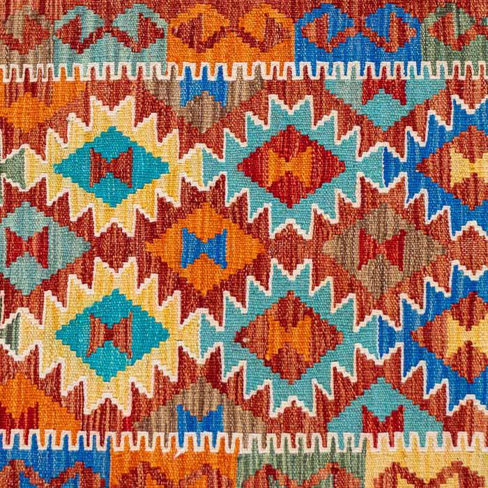 Passadeira artesanal Kilim do Afeganistão apresentando grafismos étnicos simétricos sobre trama manual plana de lã natural.