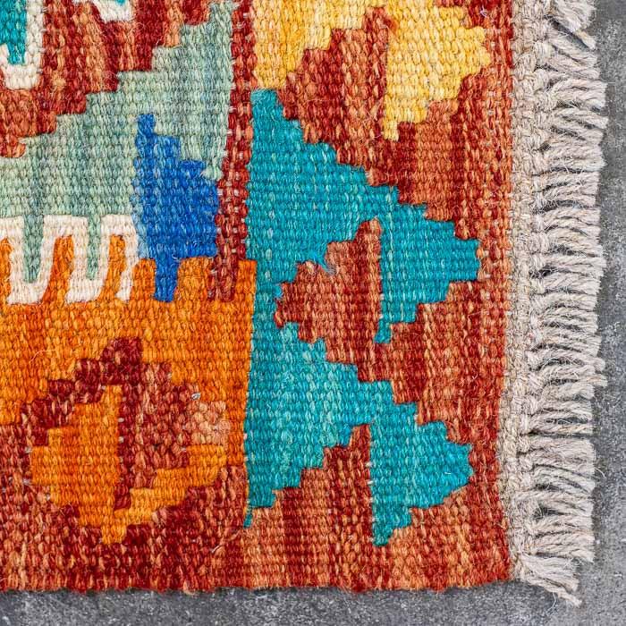 Detalhe da tecelagem manual firme de passadeira colorida destacando padrões ancestrais e acabamento artesanal em franjas.