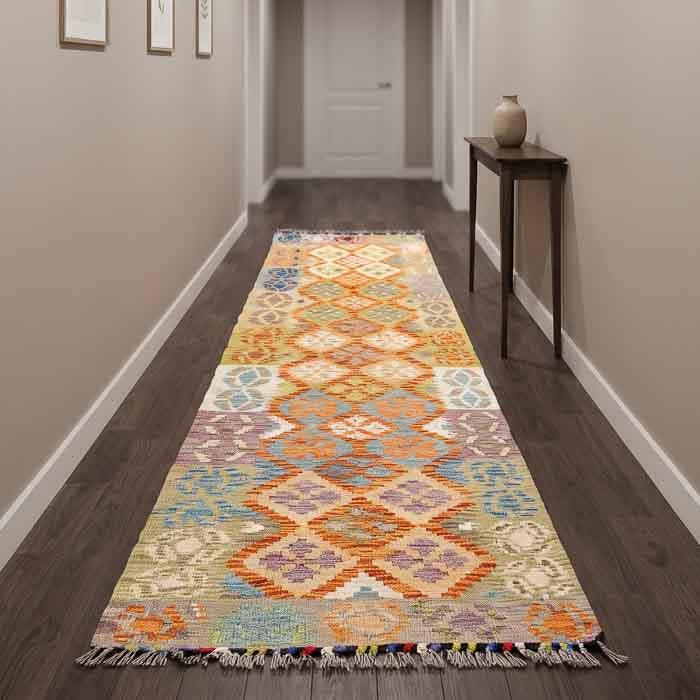 Tapete Kilim afegão oriental de 265cm em corredor iluminado com banco de couro e plantas, estilo Boho Chic exclusivo.