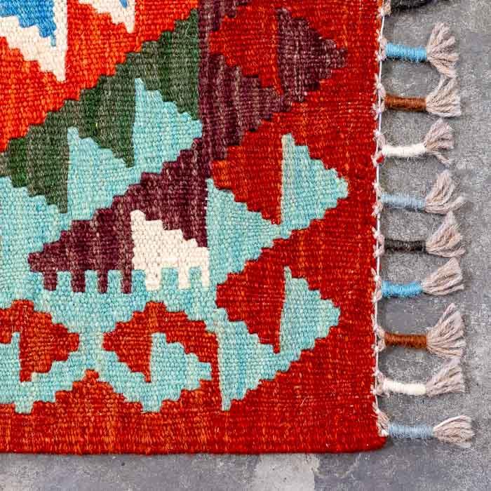 Detalhe da tecelagem manual firme de passadeira colorida destacando padrões ancestrais e acabamento artesanal em franjas.