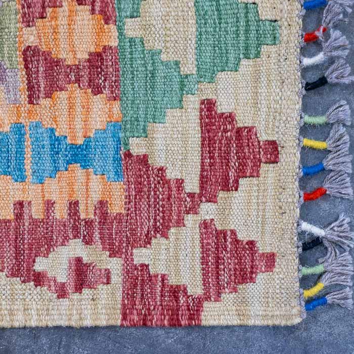Detalhe da trama plana artesanal de passadeira Kilim em fibras naturais de lã.