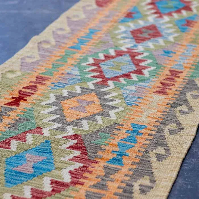 Passadeira Kilim afegã colorida tecida à mão com padrões geométricos vibrantes.